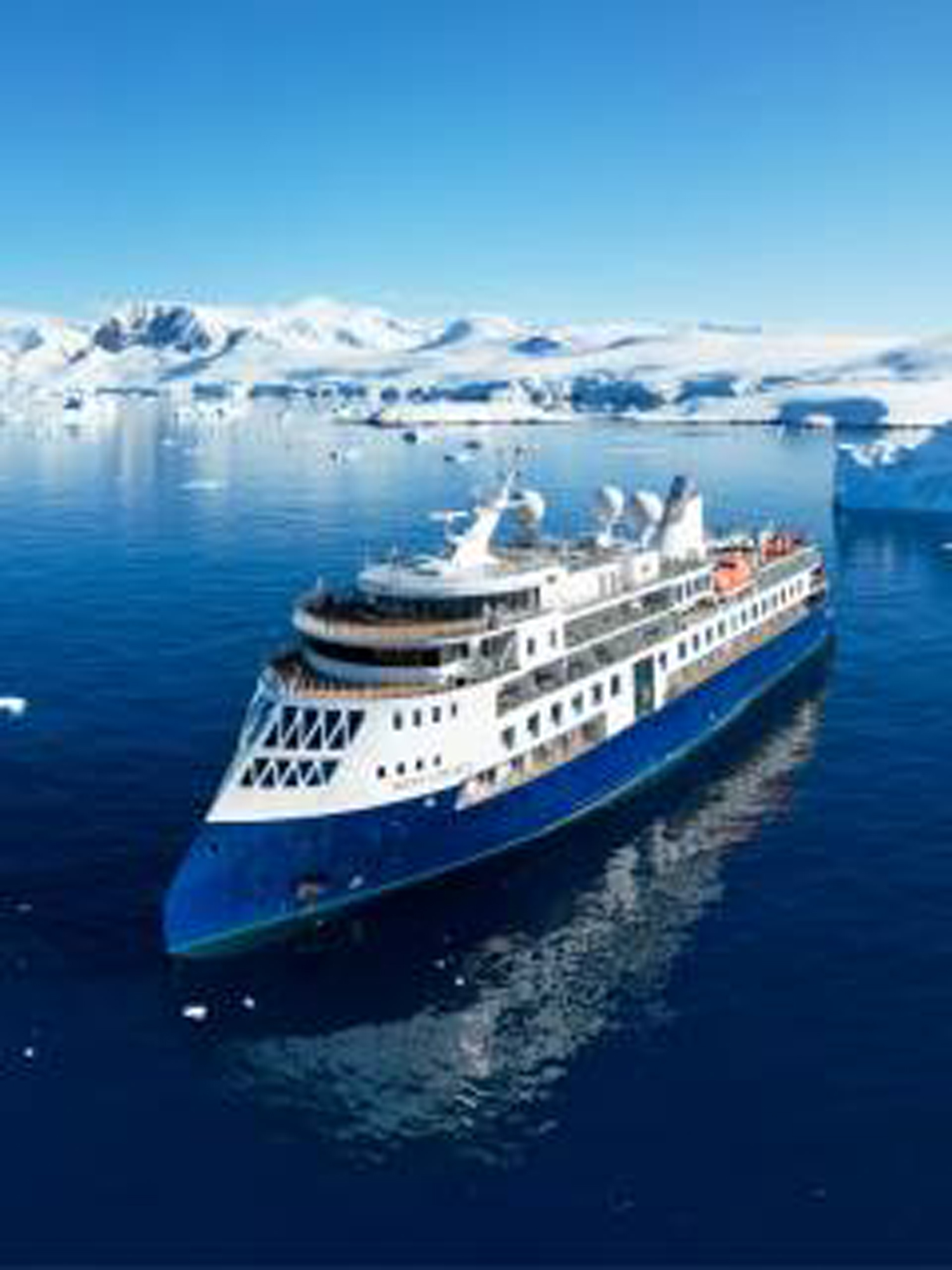 Cruise Ship Navigating Icy Arctic Waters A modern expedition cruise ship sailing through a pristine polar seascape with snow-covered mountains and floating icebergs in the background. The vessel appears designed for arctic exploration, with a sleek blue and white hull contrasting against the brilliant blue water.