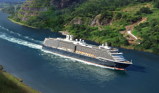 Cruise Ship Navigating Scenic Canal Passage A large modern cruise ship sailing through a lush, green narrow waterway with rocky cliff sides. The vessel is moving smoothly through the blue water, creating a white wake behind it.