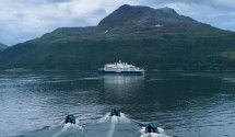 Cruise Ship in Glacier Bay Mountain Waters A white cruise ship anchors in pristine blue-green waters surrounded by snow-capped mountains and glaciers, showcasing a classic Alaska Inside Passage cruising destination with dramatic natural scenery.
