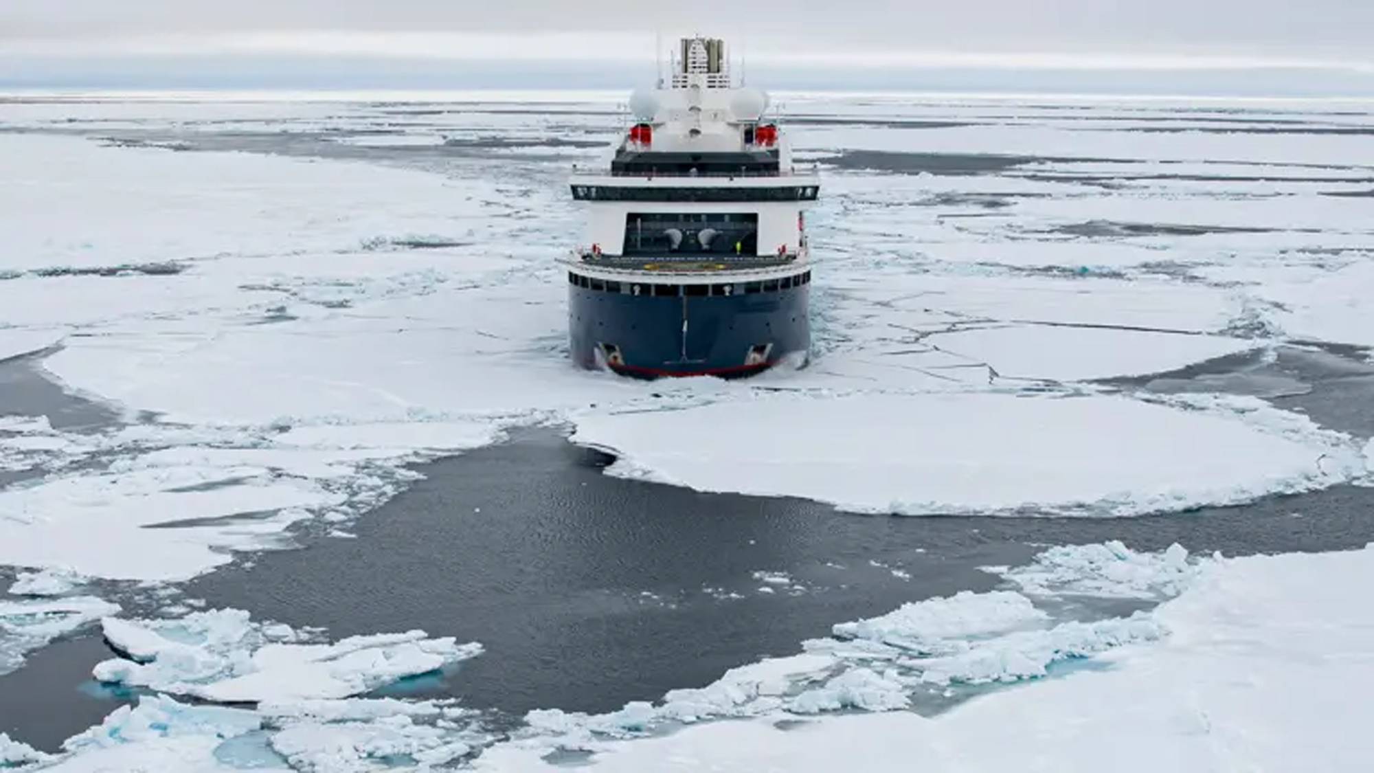Icebreaker Navigating Arctic Frozen Waters An overhead view of a polar icebreaker vessel navigating through fragmented sea ice in Arctic waters, with the ship's dark hull contrasting against white ice floes and open water channels. The image showcases the vessel's capability to break through thick ice formations in extreme polar conditions.