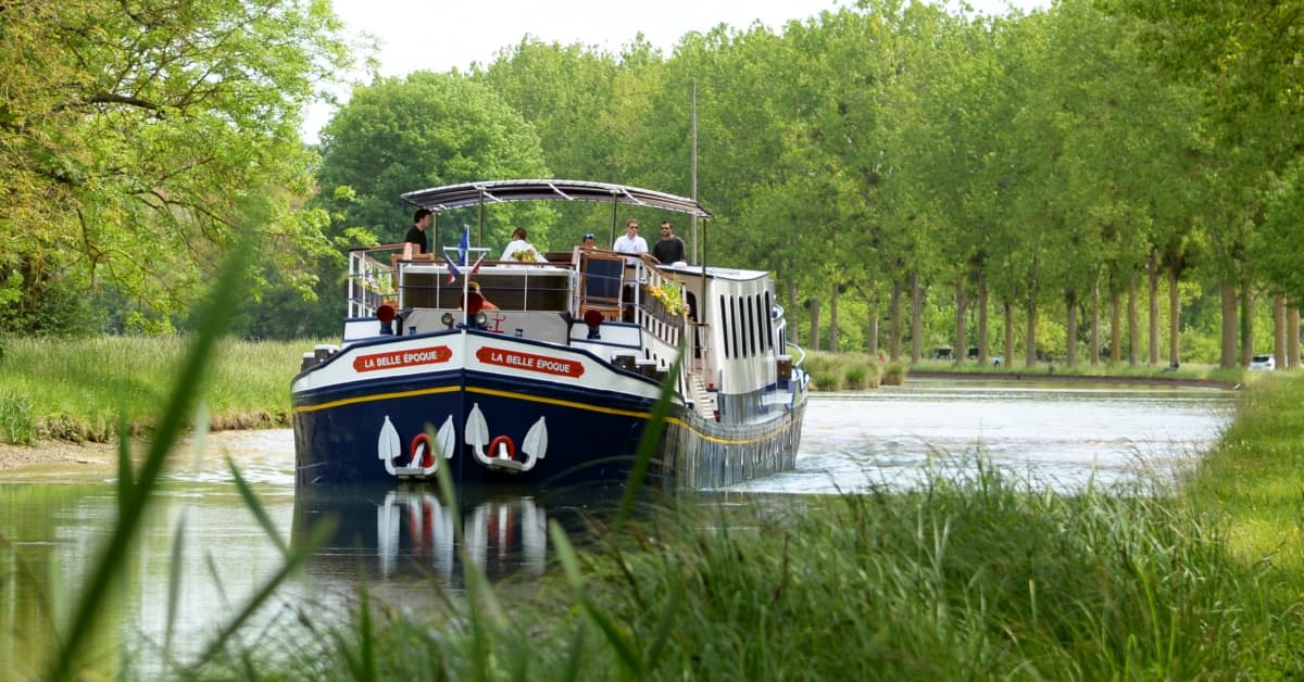 La Belle Époque River Cruise Boat A charming river cruise boat named 'La Belle Époque' navigates through a scenic waterway lined
