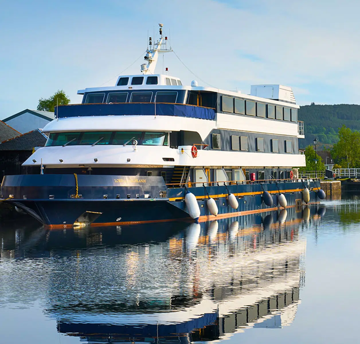 Luxury Expedition Cruise Ship Docked A sophisticated three-deck expedition cruise vessel moored at a riverside dock, featuring