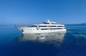 Luxury Motor Yacht in Azure Waters A sleek, white multi-deck motor yacht cruises through crystal-clear azure Mediterranean or tropical waters under brilliant blue skies. The vessel features multiple levels, contemporary design with a white hull, and appears to be a luxury expedition or mega-yacht suitable for upscale cruise experiences.