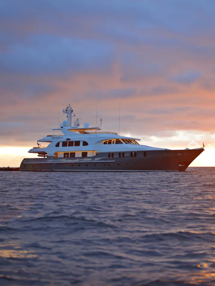 Luxury Yacht at Sunset A stunning multi-deck luxury yacht is anchored in calm waters during golden hour, with warm