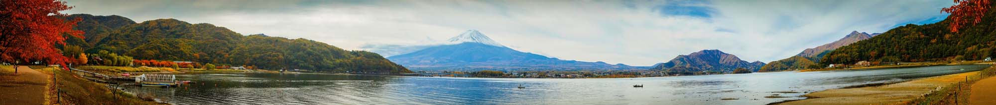 Mount Fuji with Autumn Lake Landscape A panoramic view of Mount Fuji with a serene lake in the foreground, surrounded by mountains with vibrant autumn foliage in red and green colors.
