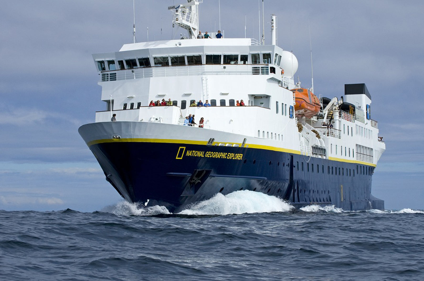 National Geographic Explorer Expedition Cruise The National Geographic Explorer, a state-of-the-art expedition cruise ship, is shown navigating through rough ocean waters with passengers visible on multiple decks. The vessel features the distinctive dark blue hull with yellow stripe and white superstructure characteristic of National Geographic's fleet, designed for exploration and adventure travel to remote destinations.