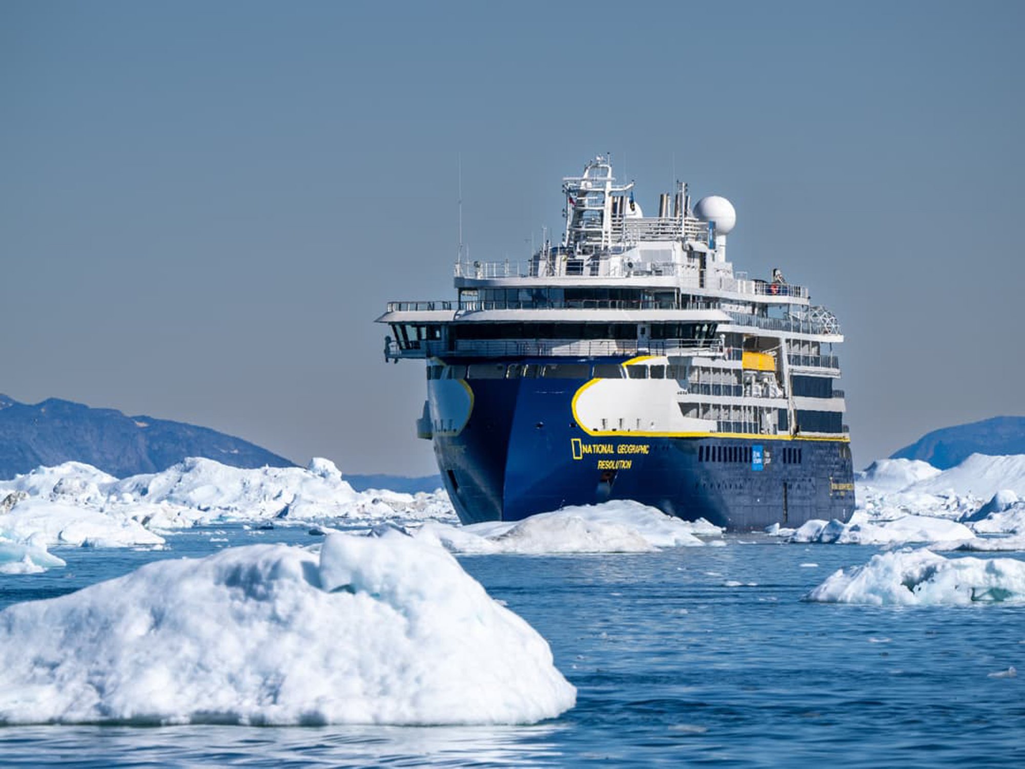 National Geographic Resolution in Antarctic Ice The National Geographic Resolution cruise ship navigates through icebergs and pack ice in Antarctica, surrounded by snow-covered mountains and pristine glacial landscape. This expedition vessel is designed for polar exploration and offers passengers an immersive experience in one of the world's most remote and spectacular destinations.