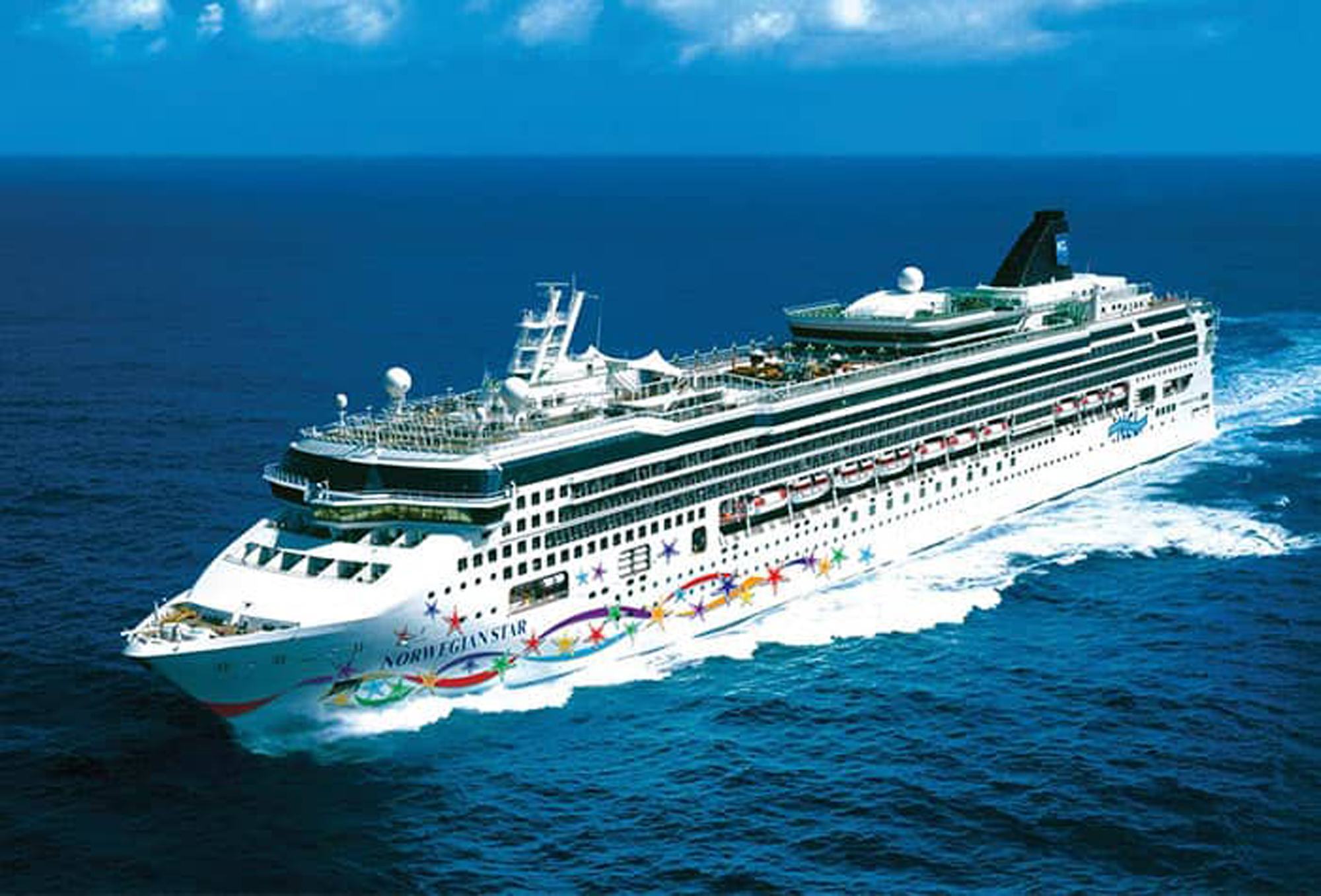 Norwegian Star Cruise Ship at Sea A large white Norwegian Star cruise ship sailing through deep blue ocean waters, decorated