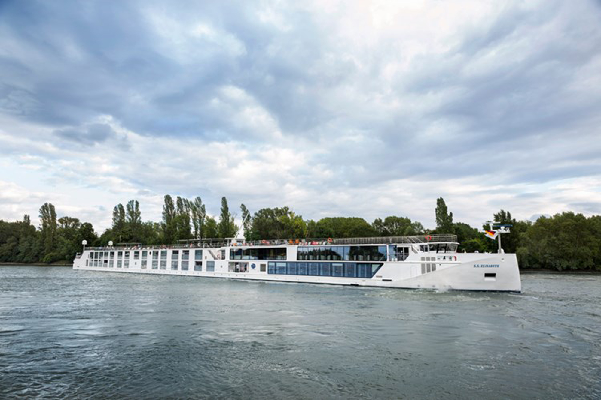 River Cruise Ship on Scenic Waterway A sleek, white river cruise vessel sailing on a tranquil river, surrounded by lush green trees