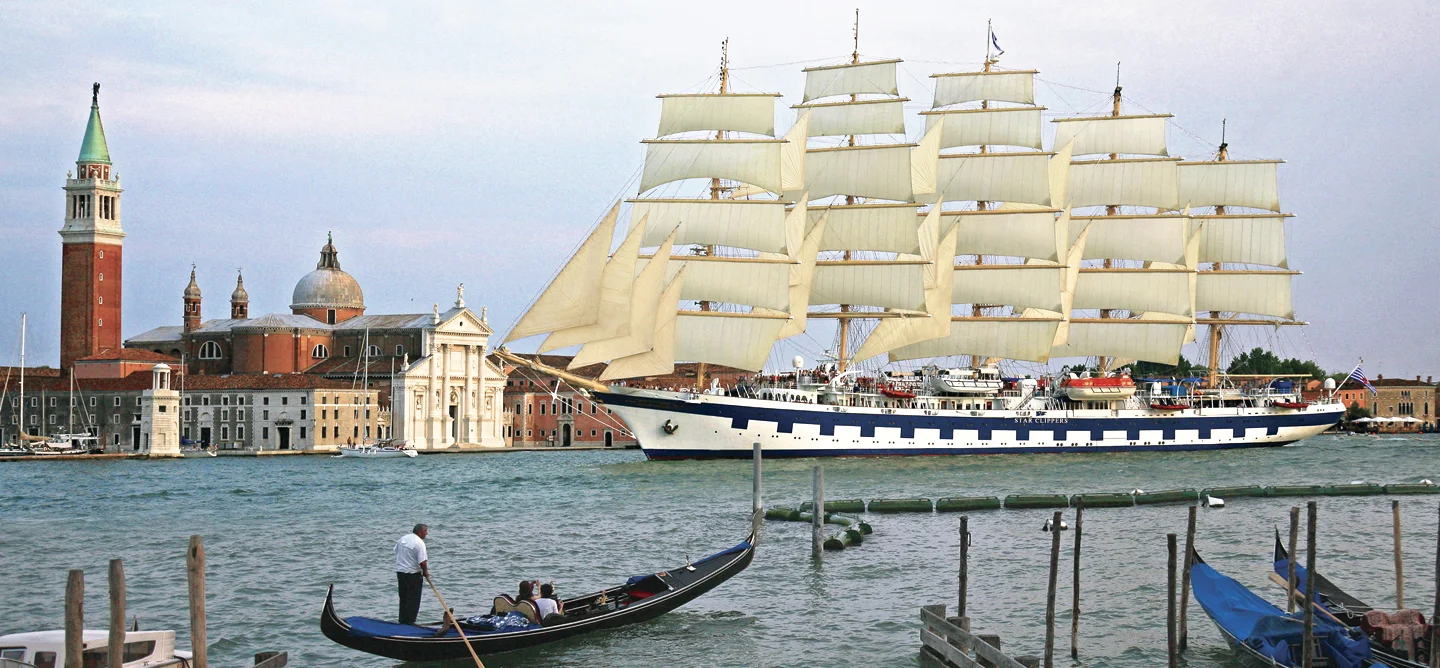Tall Ship in Venice Harbor A magnificent multi-masted sailing vessel with full white sails anchored in the Venice lagoon, with historic Italian architecture and landmarks in the background.