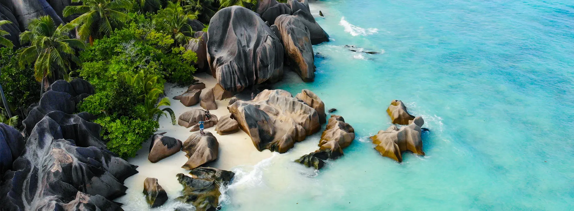 Tropical Paradise Beach with Granite Boulders A stunning tropical beach cove featuring distinctive large granite boulders scattered across pristine white sand, surrounded by crystal-clear turquoise waters and lush green vegetation, creating an idyllic destination for cruise ship excursions.