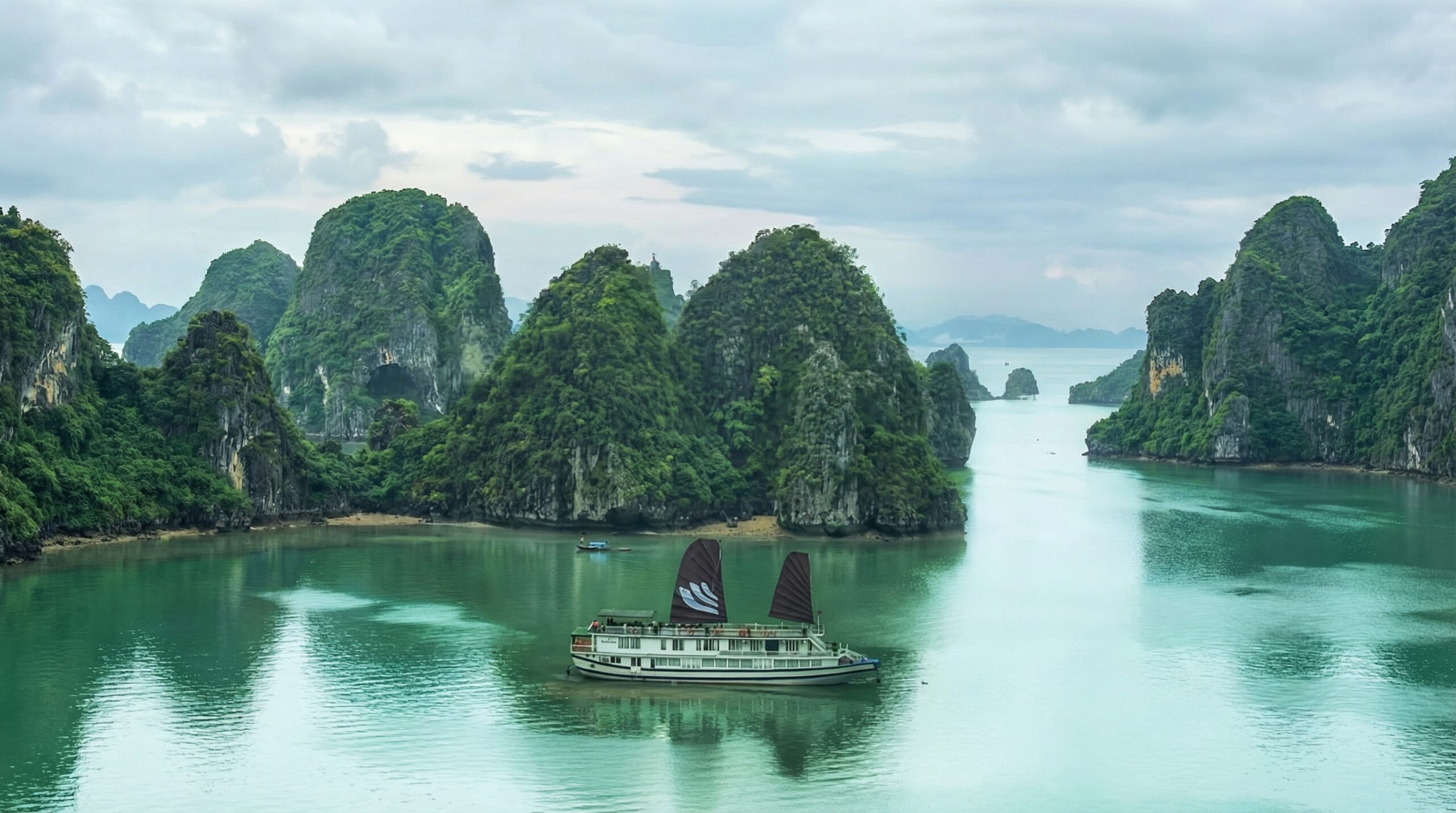 t-as-vietnam-bhaya-classic-junk-overview-1-supplied Bhaya Classic junk with dark sails in Halong Bay surrounded by limestone karsts