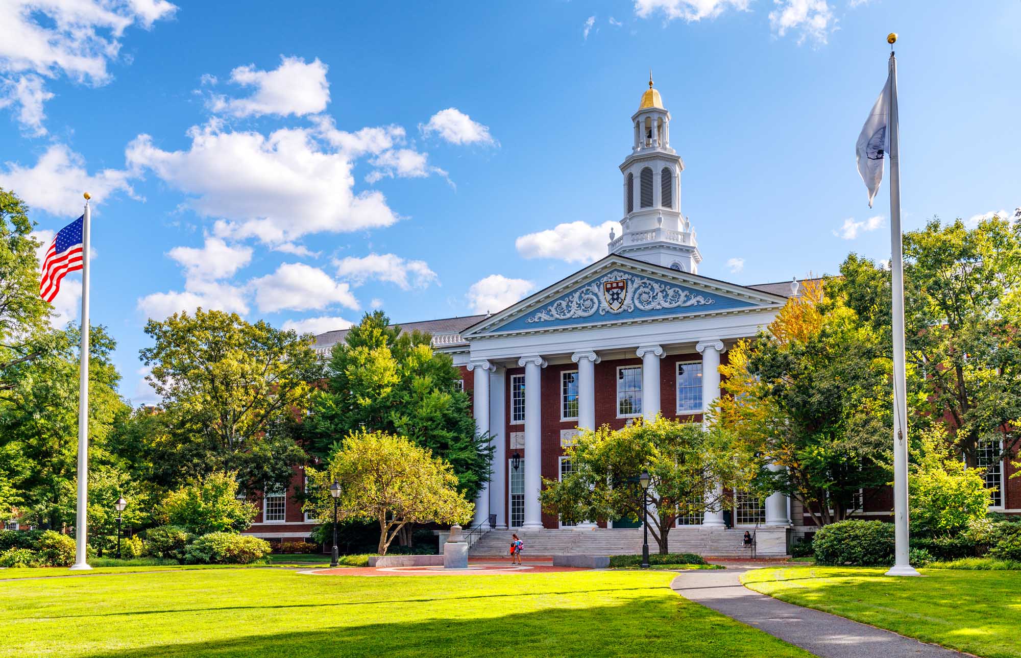 Baker Library at Harvard Business School Baker Library, the world's largest business library, stands prominently on the Harvard Business School campus in Boston. Built in 1927 and named after benefactor George F. Baker, this iconic neoclassical building features white columns, a distinctive cupola with a golden dome, and is surrounded by mature landscaping and manicured lawns.