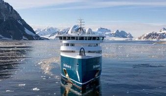 Expedition Cruise Ship in Arctic Waters A modern expedition cruise ship navigates through icy Arctic waters with snow-capped mountains