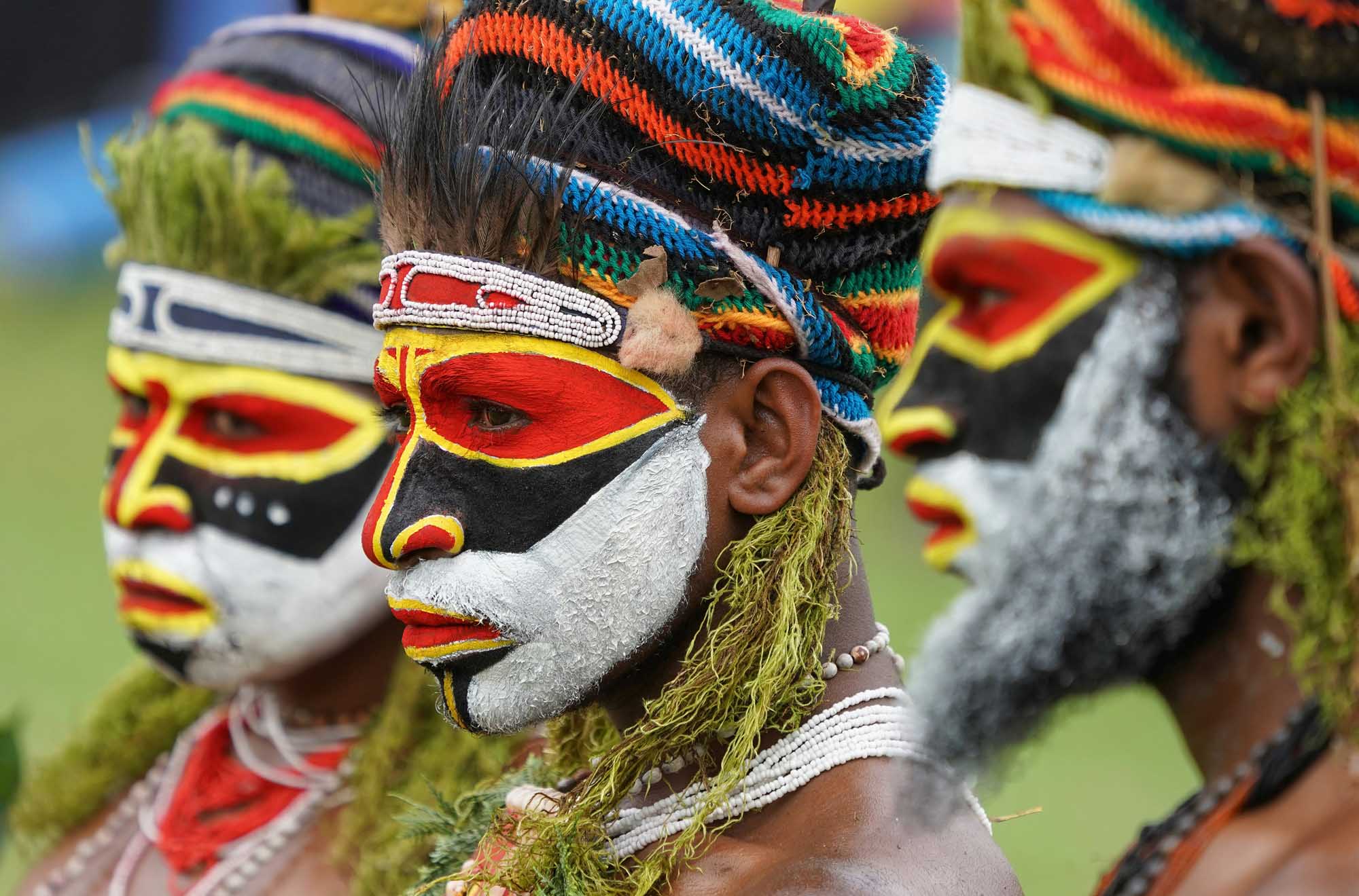 Indigenous Papua New Guinea Warriors in Traditional Dress Members of an indigenous tribe from Papua New Guinea display elaborate traditional face paint in bold red, yellow, black, and white geometric patterns, complemented by colorful woven headdresses and natural fiber decorations. This cultural portrait showcases the rich tribal heritage and ceremonial artistry of the region.