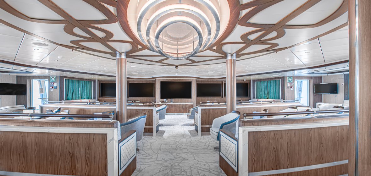 Modern Lecture Room with Circular Ceiling Design A sophisticated lecture room or auditorium featuring a striking circular tiered ceiling with wood accents and integrated lighting. The space showcases multiple seating stations with curved brown wood paneling, turquoise accents, and a geometric patterned floor, designed for presentations or educational purposes in a contemporary maritime setting.