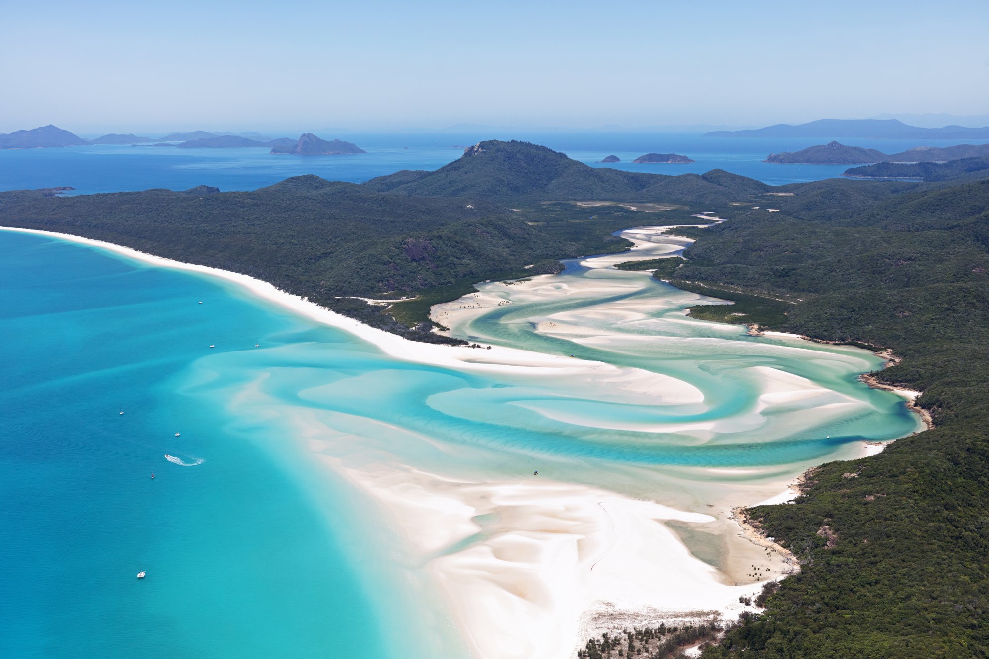 Whitehaven Beach Aerial View, Whitsunday Islands An aerial panorama of Whitehaven Beach on Whitsunday Island, Australia, showcasing the iconic white silica sand beach with turquoise lagoons, surrounding rainforest-covered hills, and numerous small islands dotting the sapphire waters of the Coral Sea.