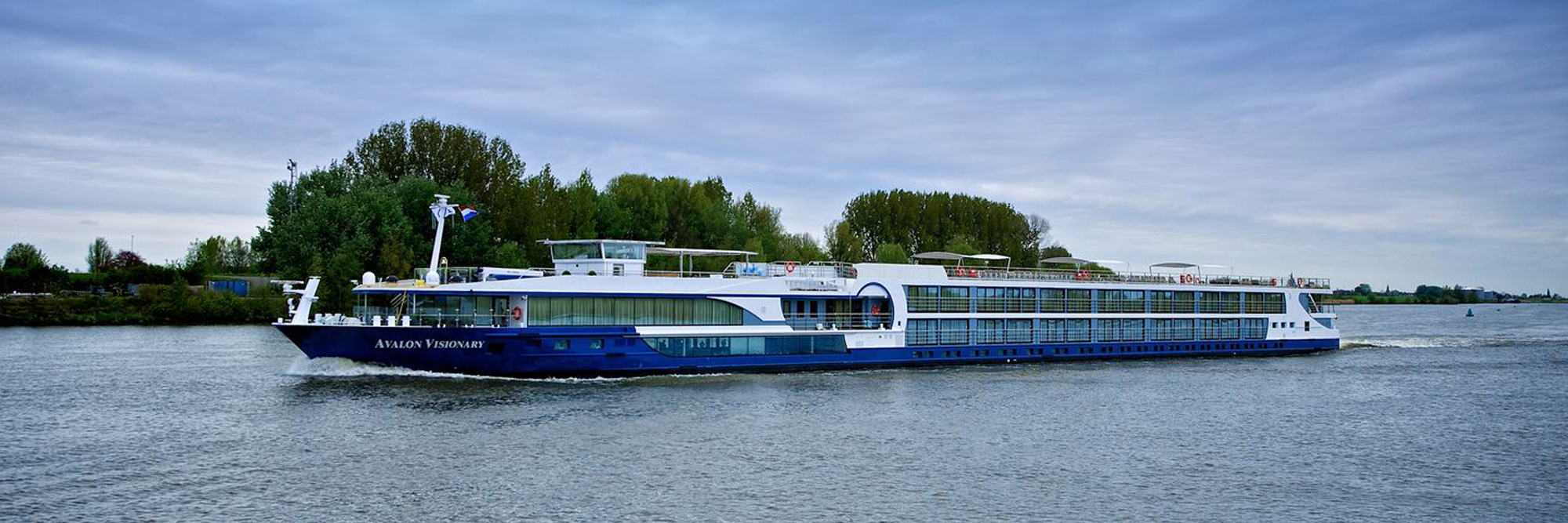 Avalon Visionary River Cruise Ship The Avalon Visionary, a modern river cruise ship, sails through a scenic waterway lined with lush