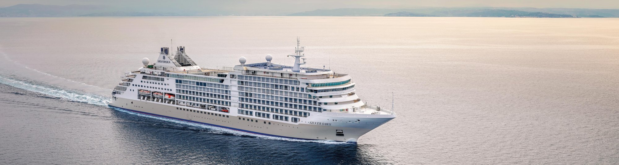 Silversea Cruise Ship at Sea A large luxury cruise ship from Silversea navigates through calm waters with distant mountains