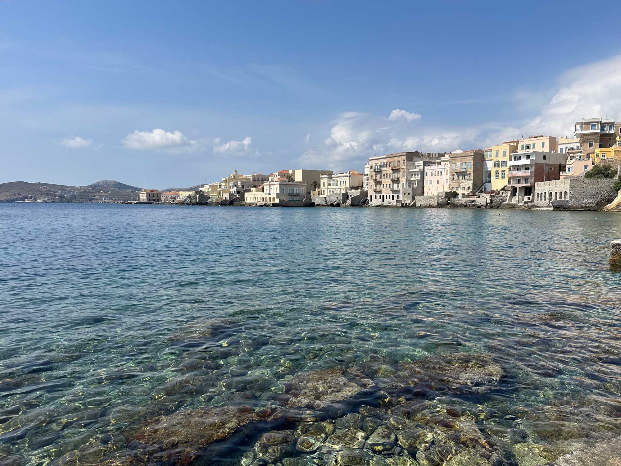 Colorful Waterfront Village on Aegean Sea A picturesque Mediterranean coastal village with vibrant pastel-colored buildings cascading down
