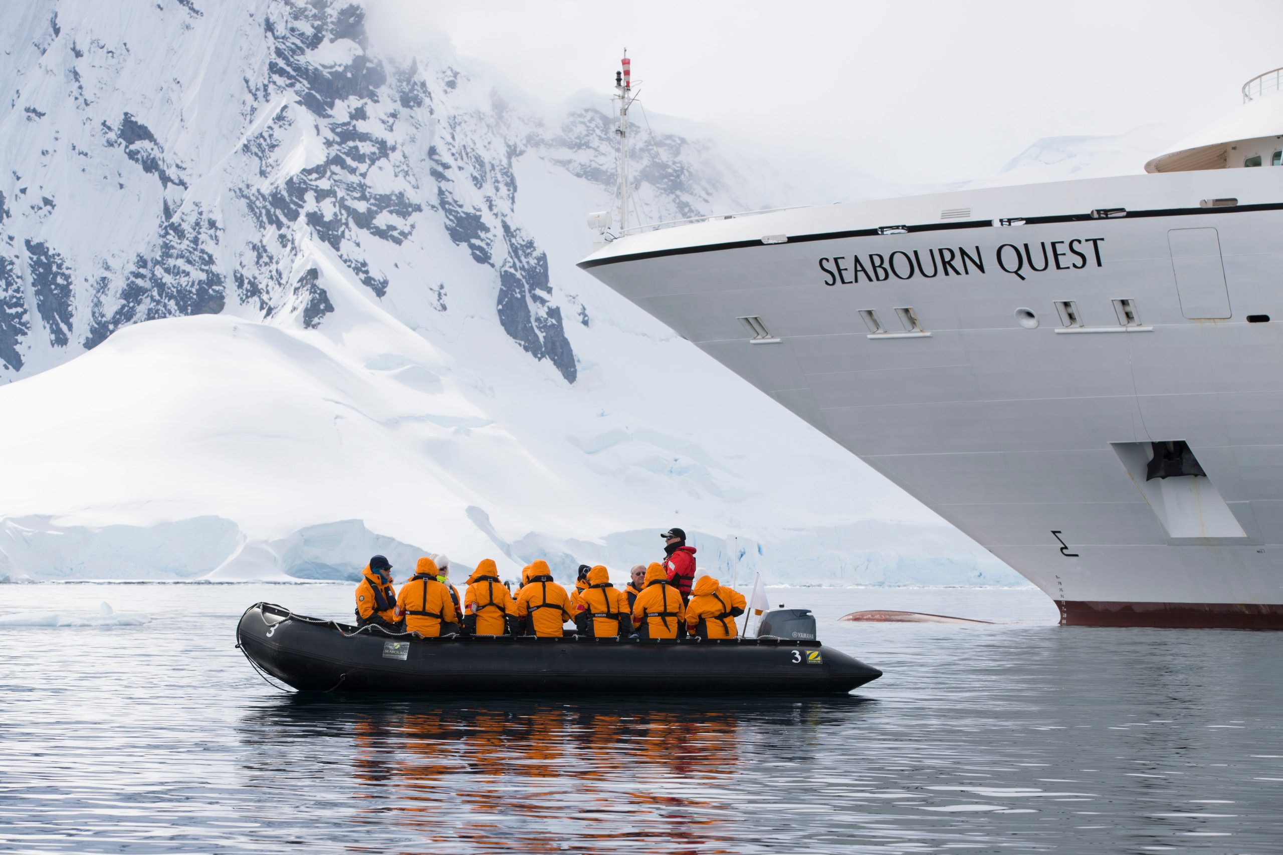 Seabourn Quest Zodiac Excursion in Antarctica Passengers in a black Zodiac inflatable boat wearing bright orange life jackets prepare for